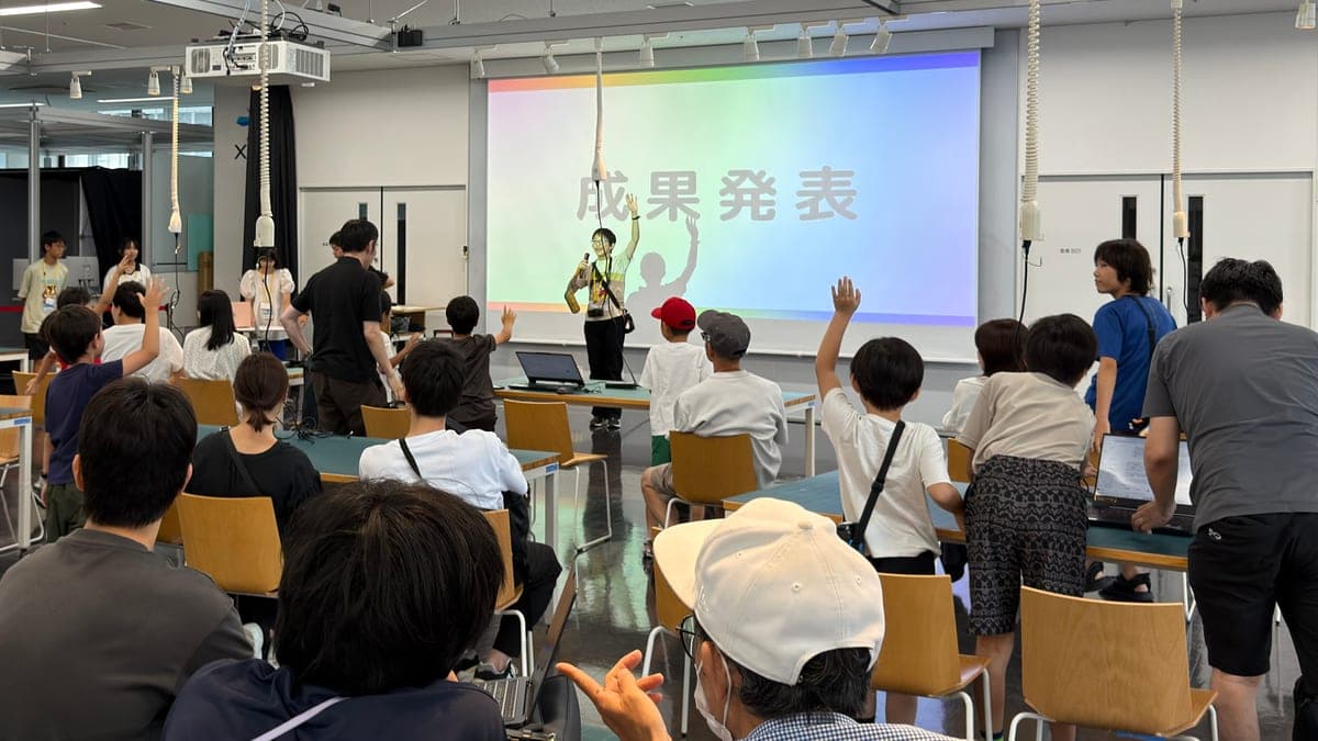 共創型ワークショップの成果発表の様子。子どもと大人が同じ会場に集まり、手を挙げて発表に参加している